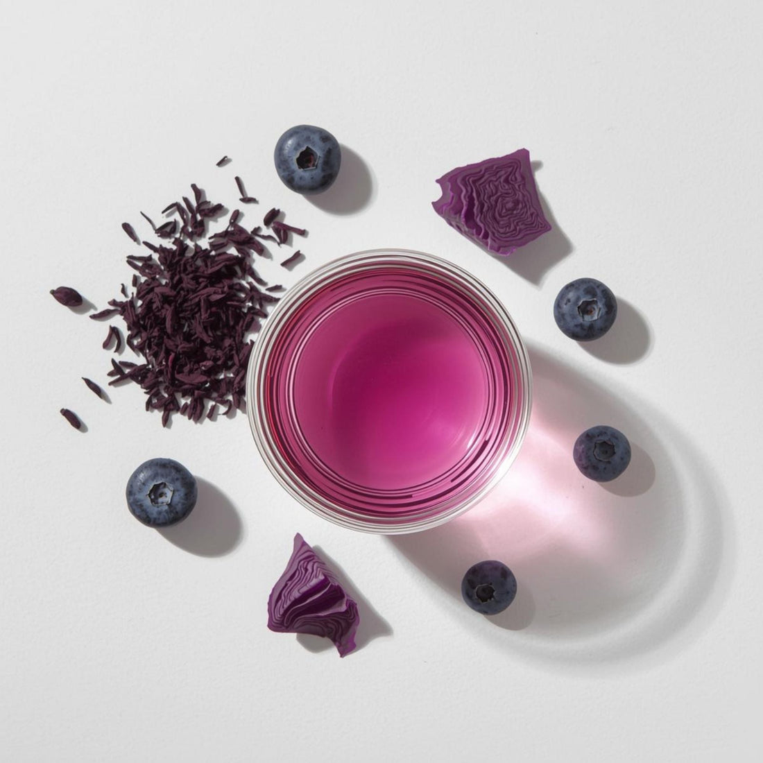 purple tea in glass cup showing natural anthocyanin color on white background