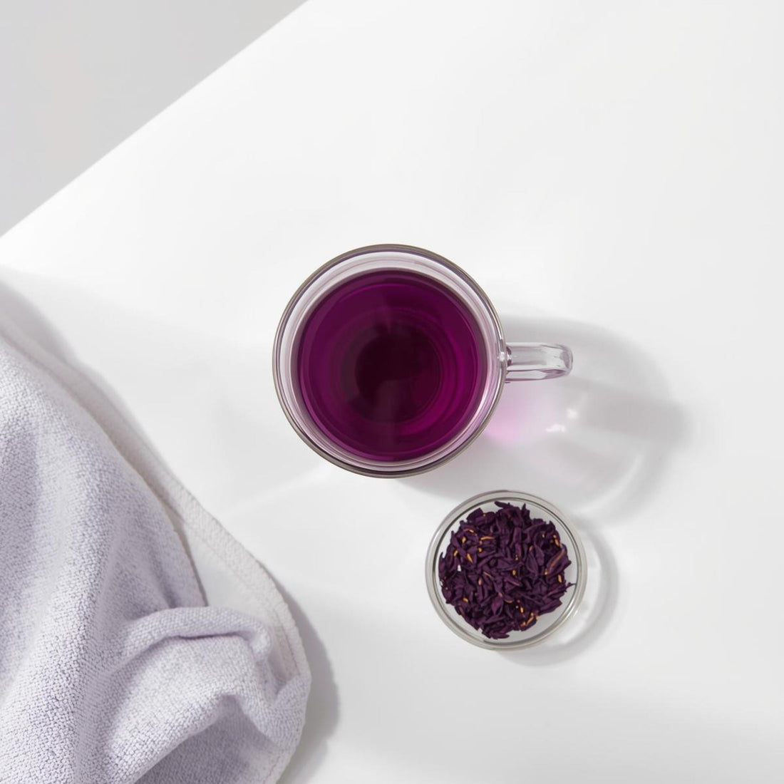 Top view of purple tea in a glass cup with dried purple leaves, representing research on GHG and metabolic health