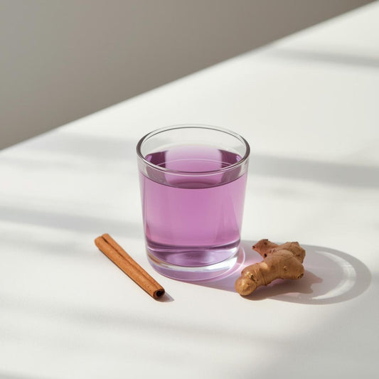 Glass of purple tea with cinnamon stick and fresh ginger illustrating spice infusion and antioxidant balance