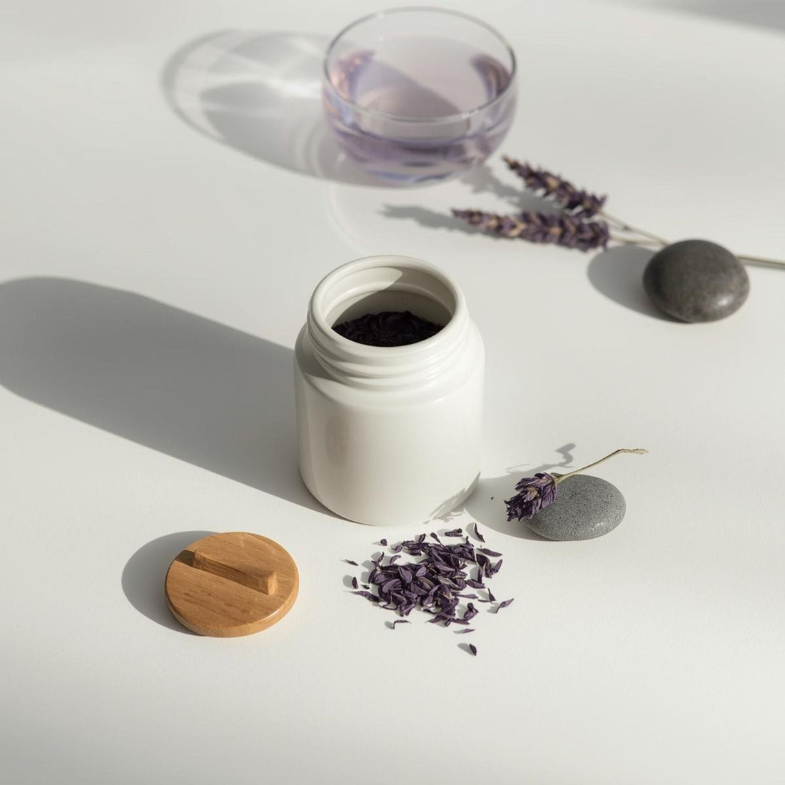 purple tea stored in minimalist glass teacup on white surface