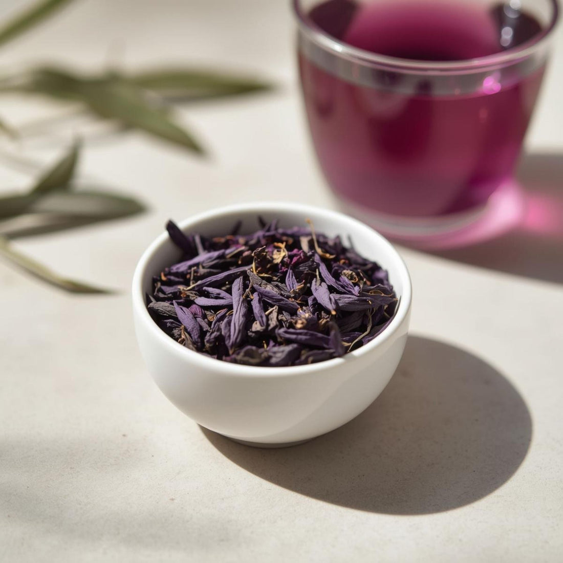 Dried purple tea leaves from TRFK 306/1 cultivar with brewed purple tea in background