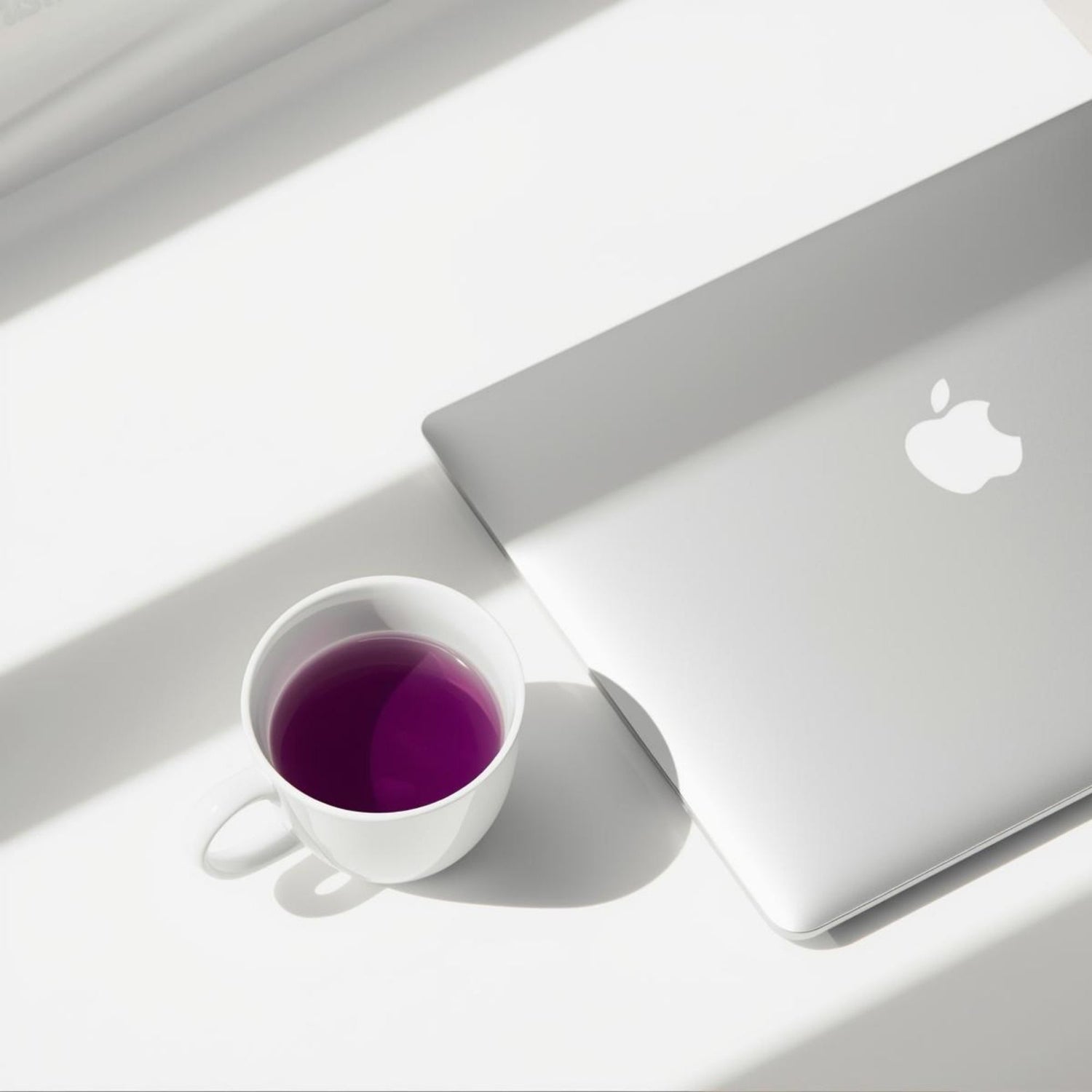 Minimal white cup of purple tea on a clean desk next to a laptop